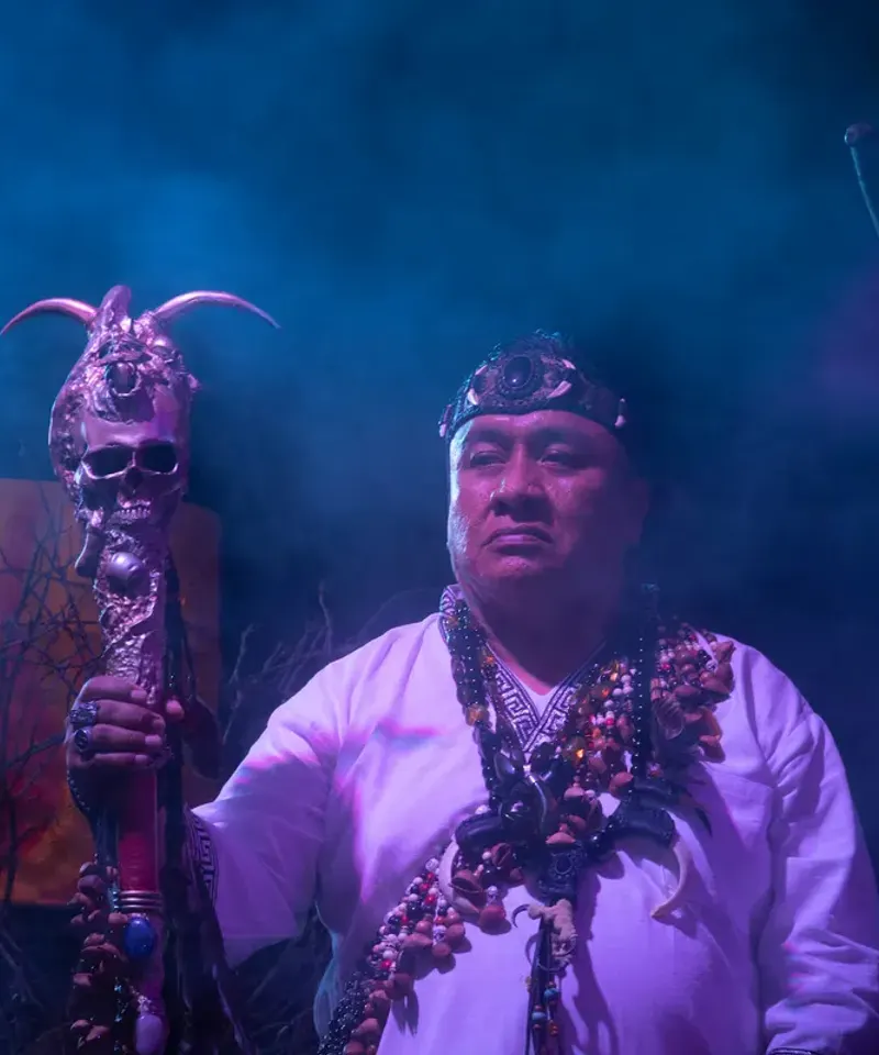 Chamán con báculo y cráneo ritual ofreciendo consulta de brujería