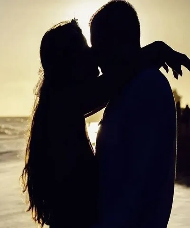 Silueta de pareja besándose en playa al atardecer